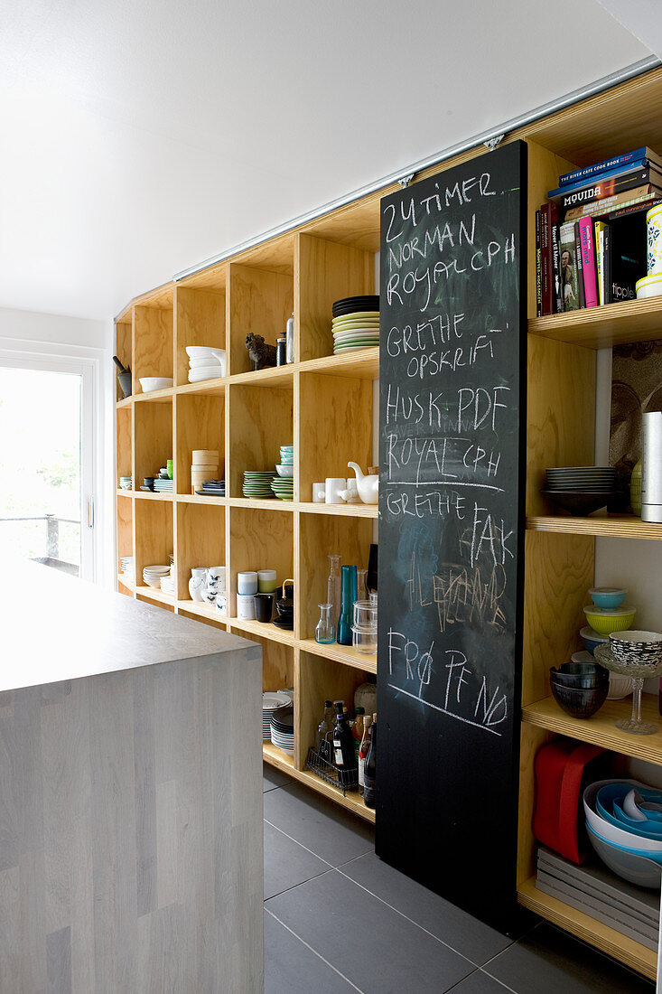 Chalkboard sliding door flanked by shelves of crockery in kitchen