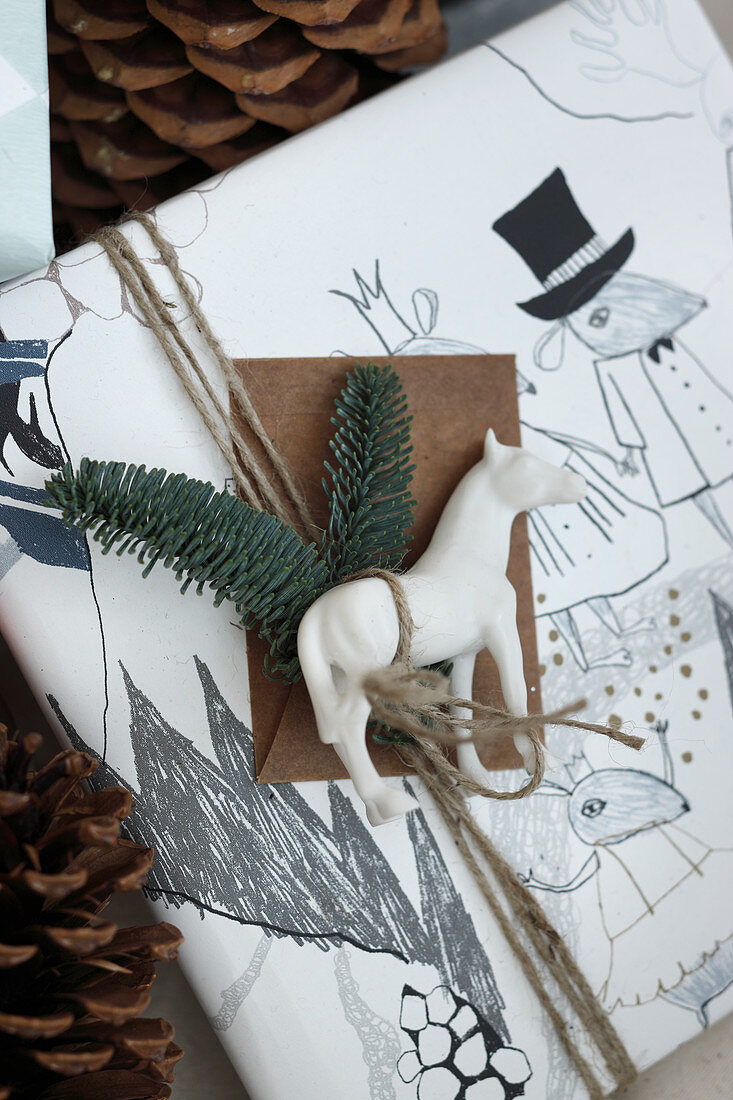 Weißes Pferd und Tannenzweige auf einem verpackten Geschenk