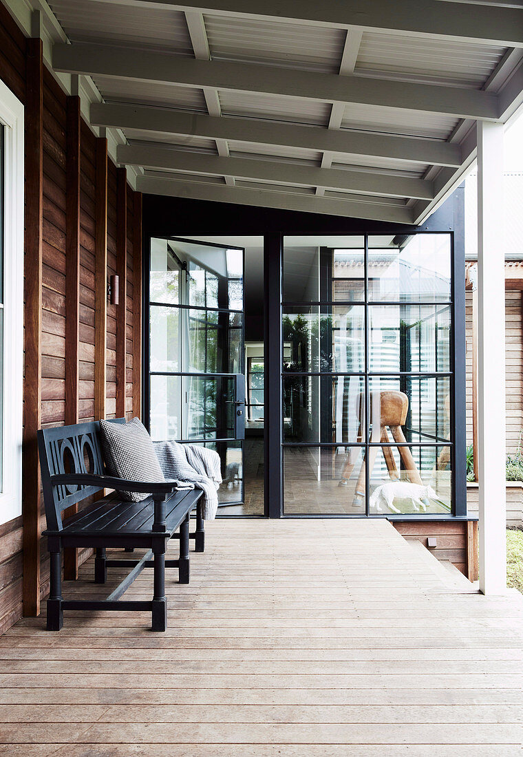 Black bench on the veranda with plank floor at the wooden house
