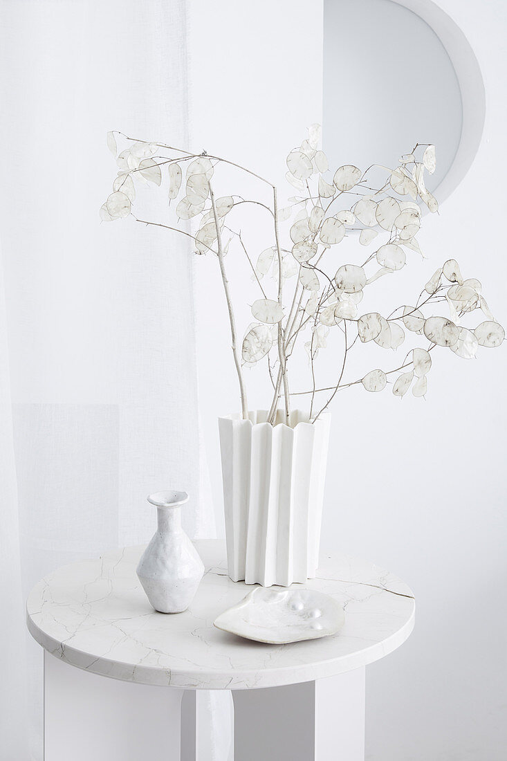 Deko in Weiß: Silberblattzweige in einer Zickzack-Vase auf Beistelltisch