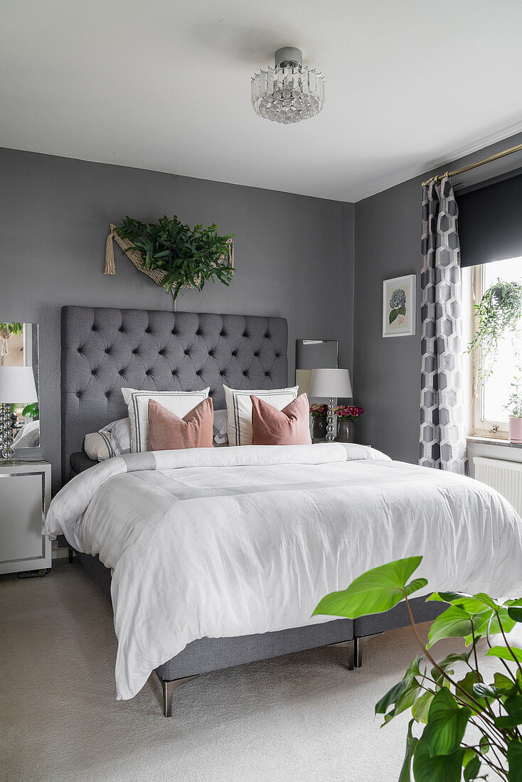 Bed with button-tufted headboard in elegant bedroom in grey and white