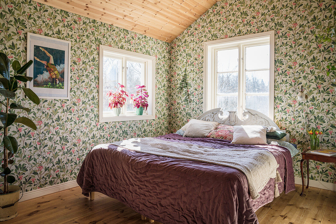 Vintage-style bed in sunny bedroom with floral wallpaper