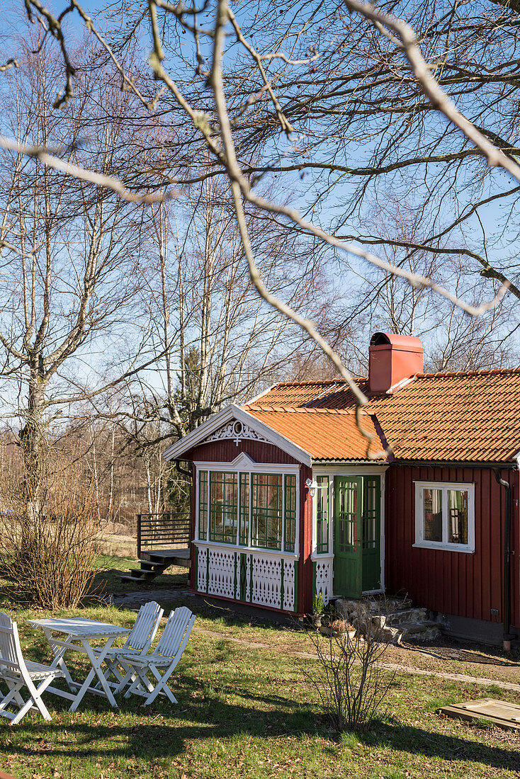 Rotes Schwedenhaus mit Wintergarten und Garten im Frühling