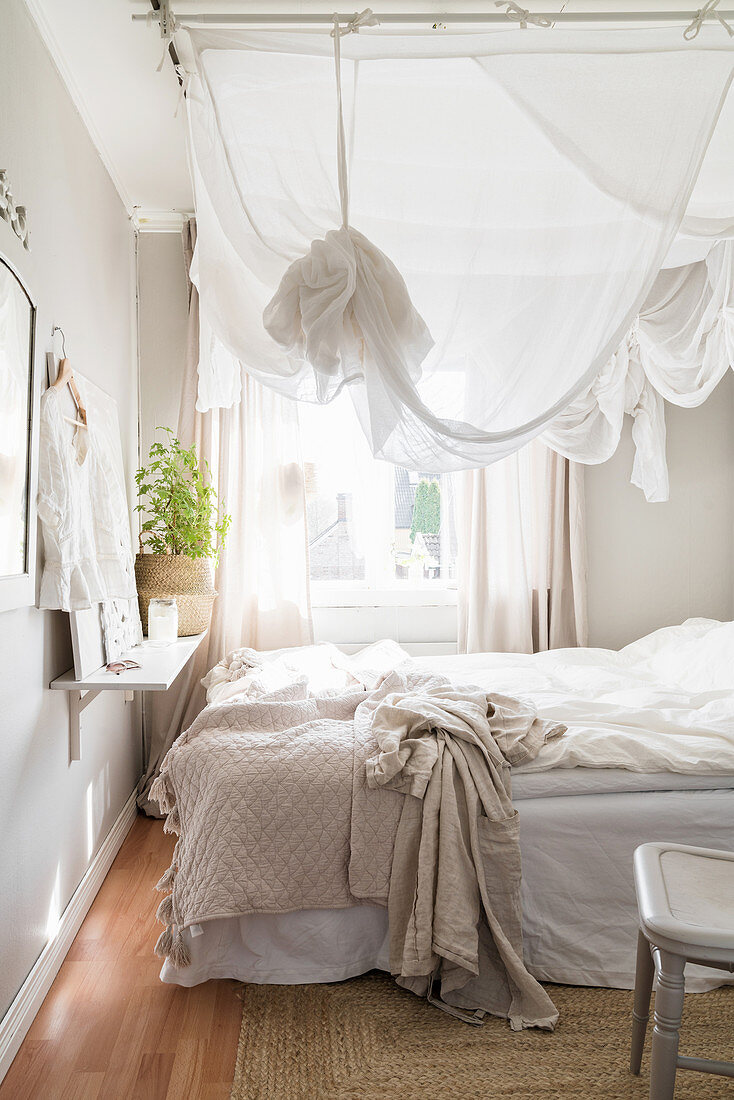 Small, white and grey bedroom with canopy over bed