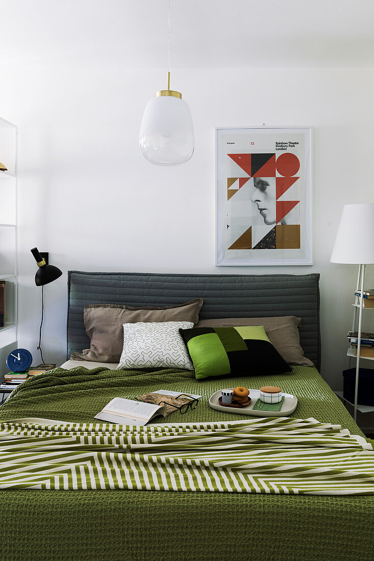 Graphic patterns in bedroom with green bedspread on bed with upholstered headboard