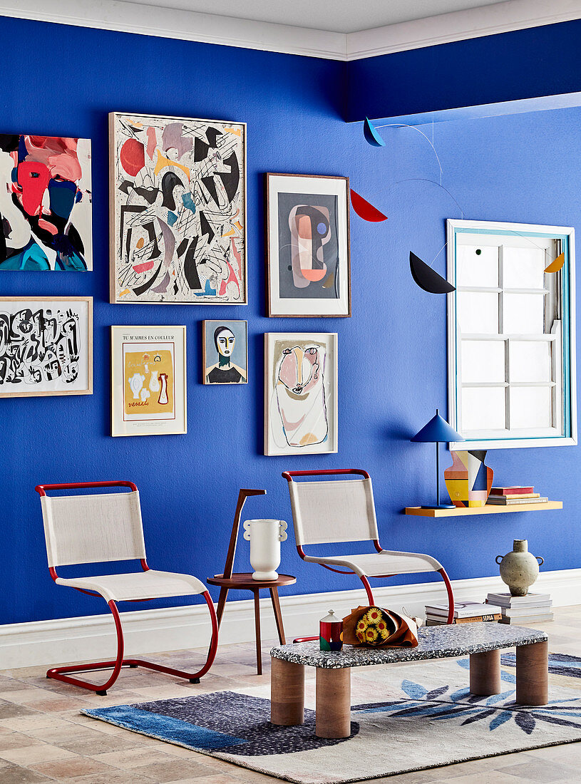 Freischwinger, Beistelltisch und niedriger Tisch im Zimmer mit Kunstwerken an blauer Wand