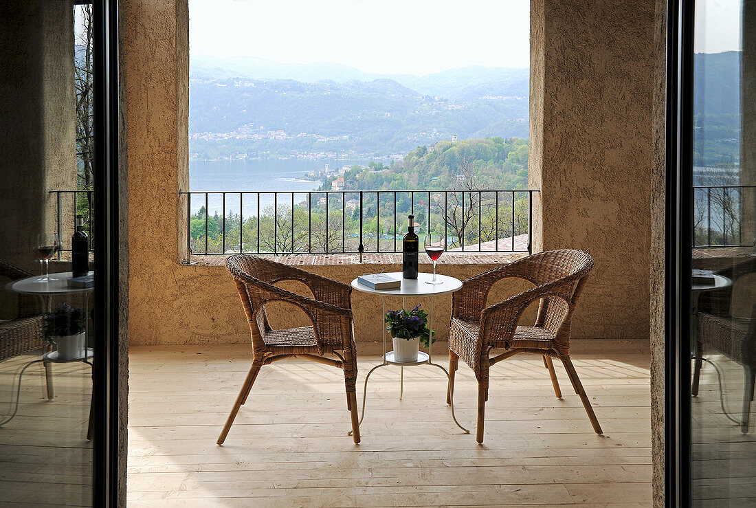 Korbsessel und filigraner Tisch auf mediterraner Terrasse mit Landschaftsblick
