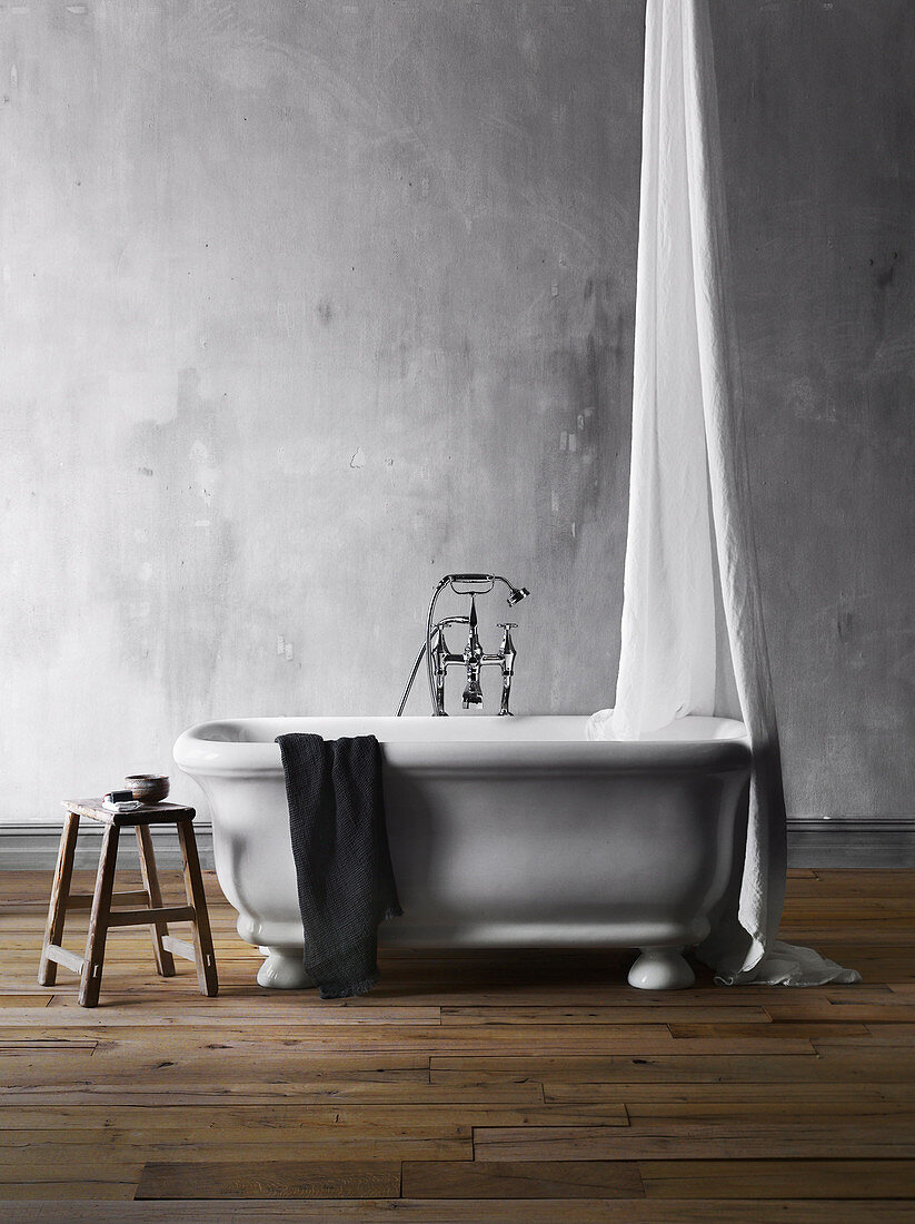 Freestanding bathtub with canopy and stool against gray wall
