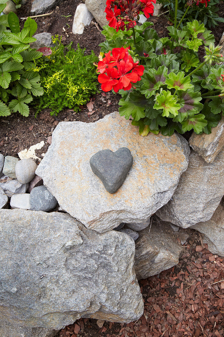 Stein in Herzform auf einer Gartenmauer aus Steinen