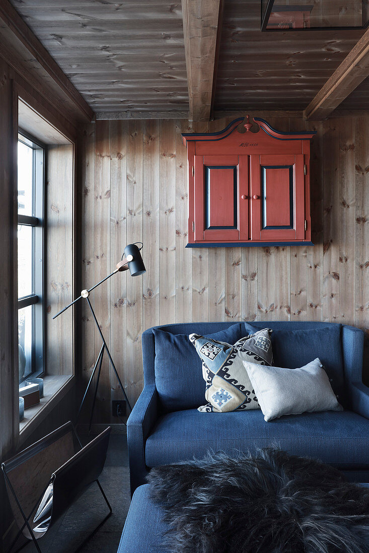 Gemütliche Sitzecke im Cottage mit blauem Sofa vor Holzwand