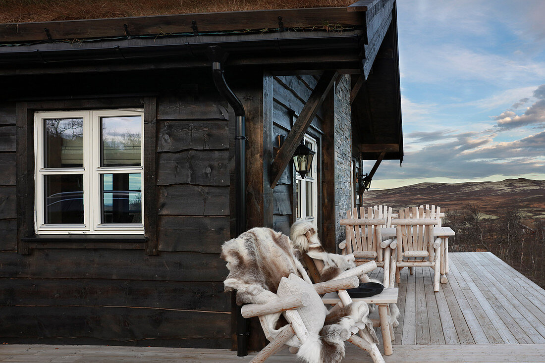 Urige Holzstühle auf Veranda eines Cottage mit imposanten Landschaftsblick