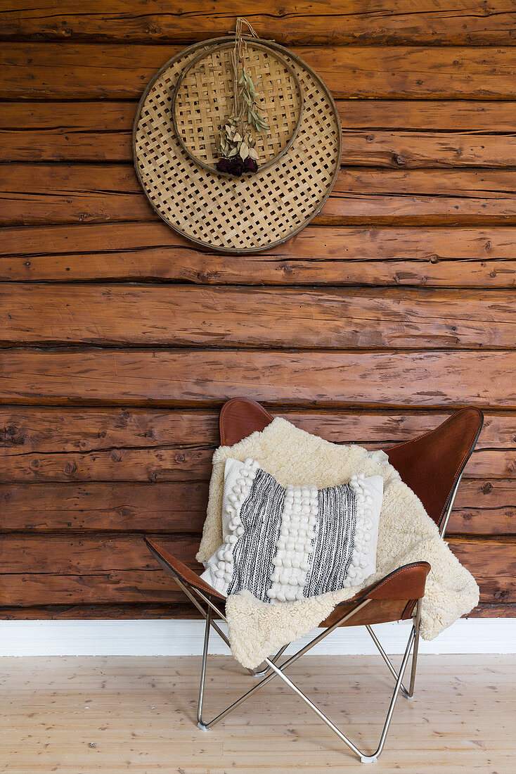 Designerstuhl aus Leder vor rustikaler Holzbalkenwand