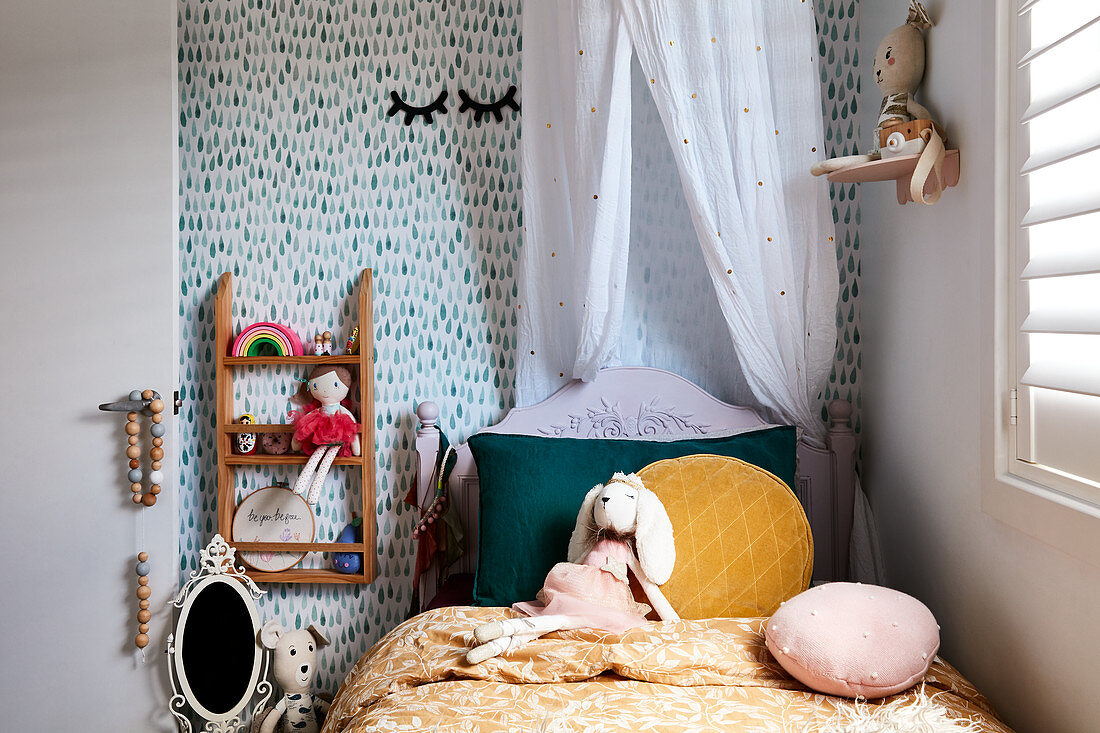Bed with canopy and patterned wallpaper in girl's bedroom
