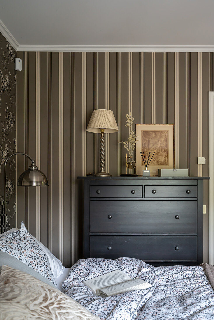 Black chest of drawers against wall with brown striped wallpaper in bedroom