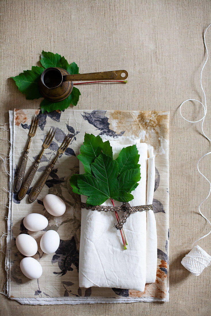 Weißer Stoff mit Weinblättern, weiße Eier, Vintage Gabel und Mokkakännchen