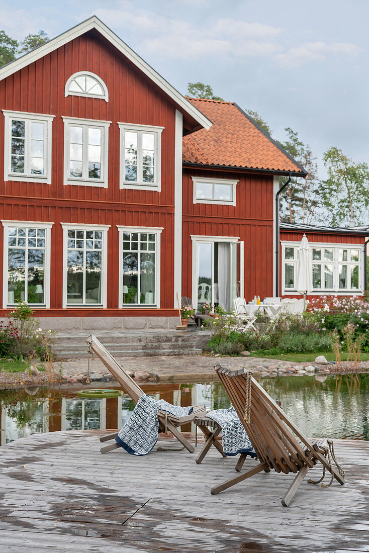 Liegestühle auf dem Steg am Teich vorm roten Schwedenhaus