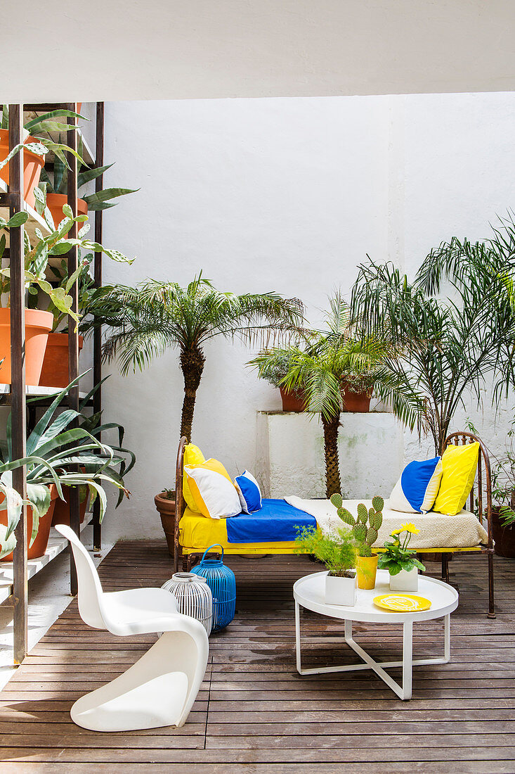 Metallett als Sofa auf sommerlicher Terrasse mit Palmen und Kakteen