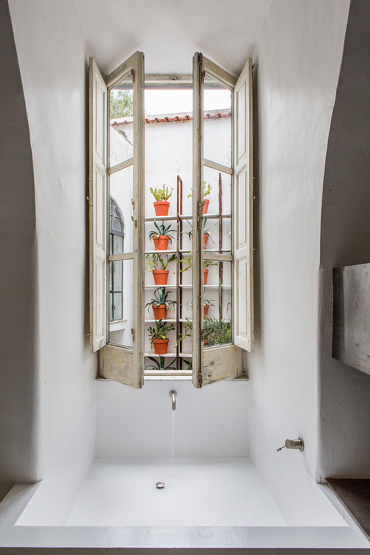 Fitted bathtub below casement window in Mediterranean bathroom