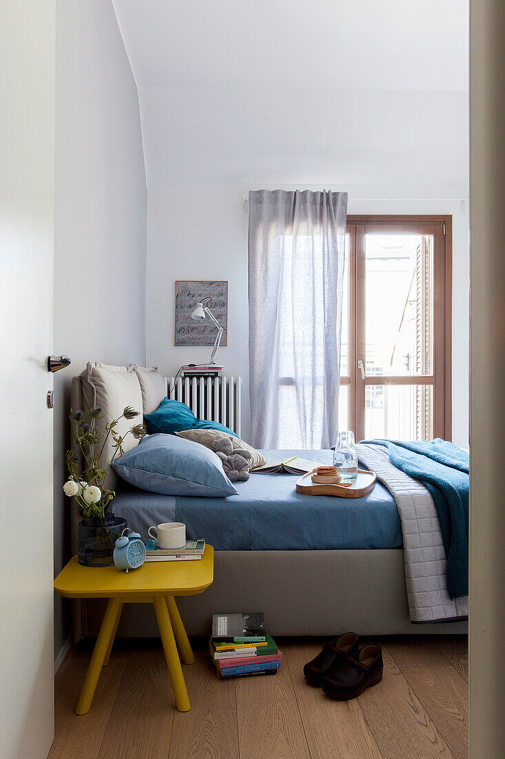 Yellow bedside table next to double bed in bedroom