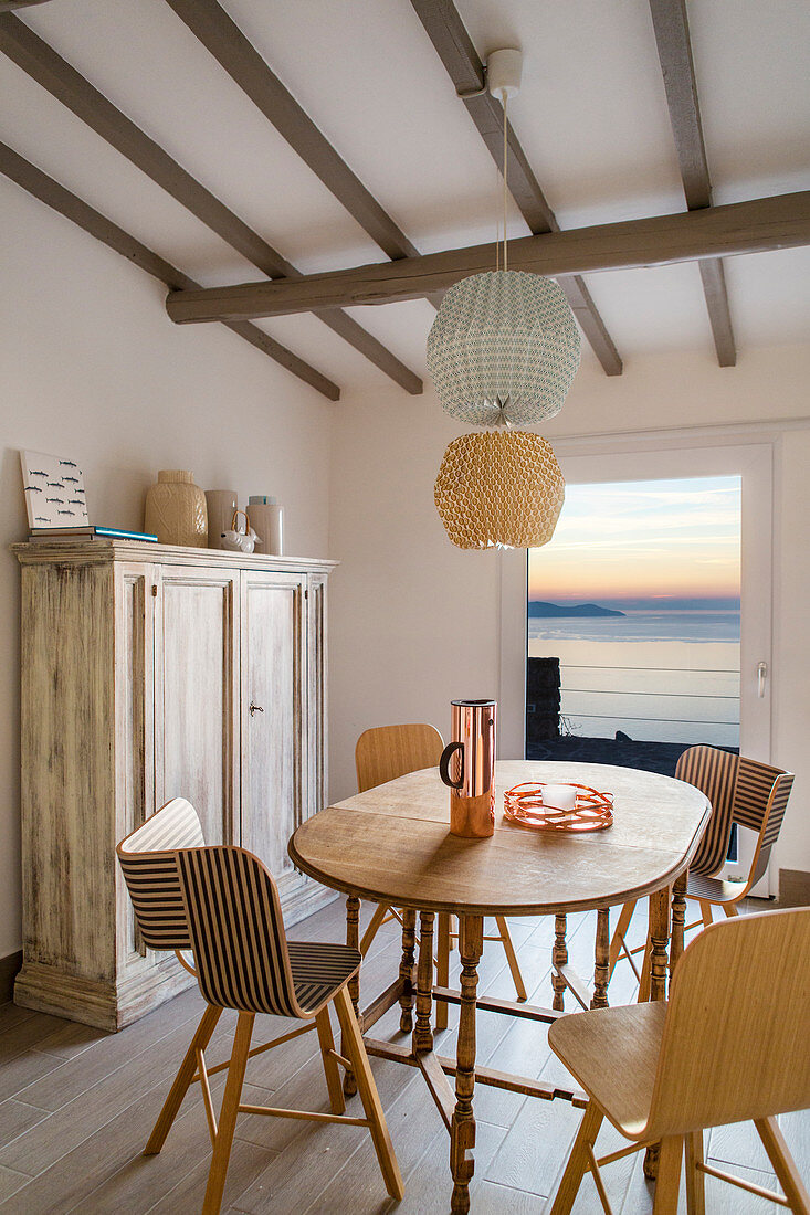 Designer chairs and dining table with sea view at sunset
