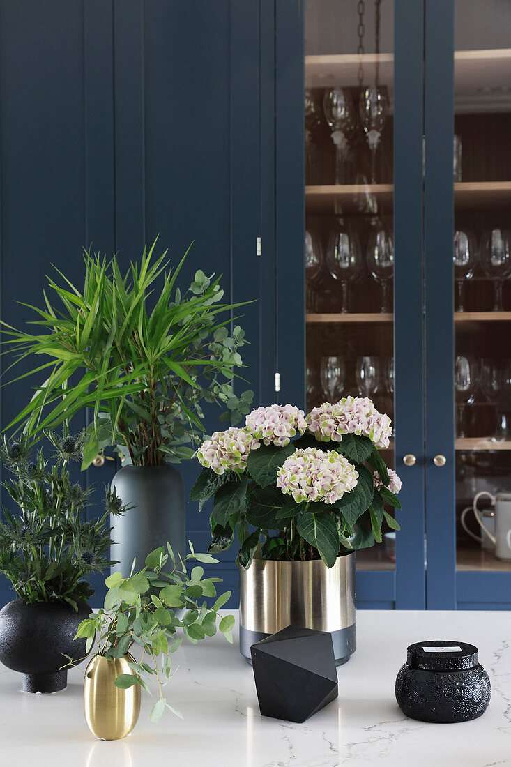 Hortensie, Disteln und Zweige in schwarzen und goldenen Vasen