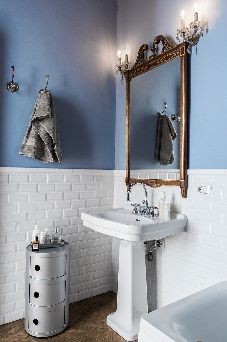 Wooden-framed mirror and old-fashioned wall lamps above vintage-style sink