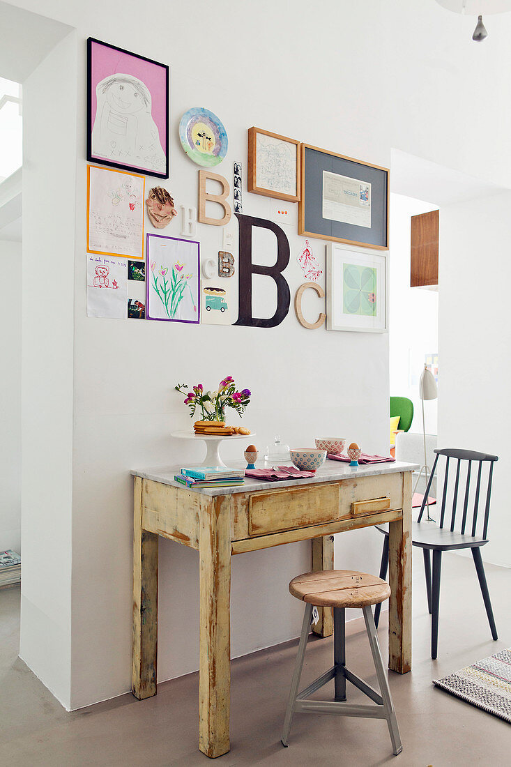 Alter schmaler Holztisch unter Bildergalerie als Frühstückstisch für Zwei