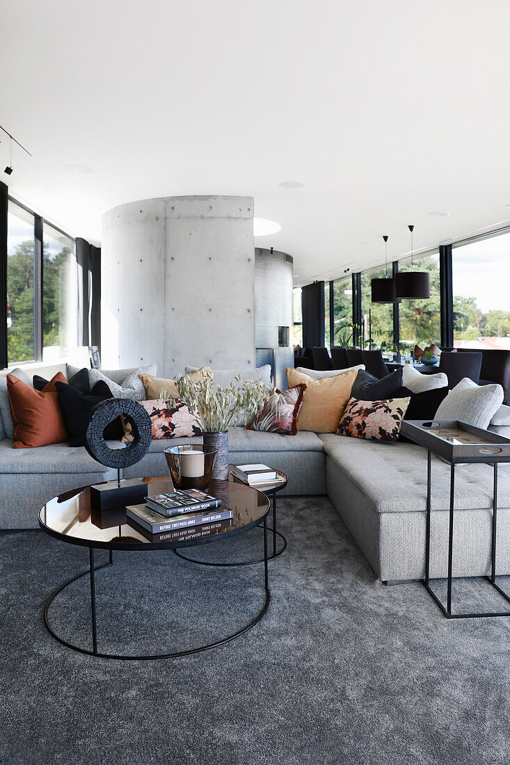 Round coffee table in front of sofa in open-plan living room in shades of grey
