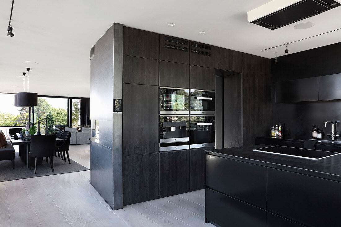 Black, modern kitchen in open-plan interior in shades of grey