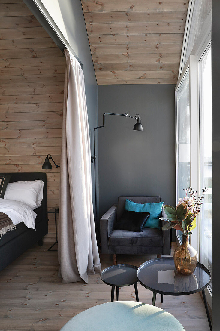 Sessel am Fenster im eleganten Schlafzimmer mit Holzverkleidung