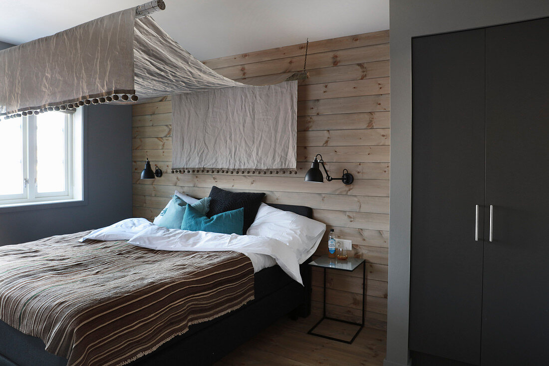 Schlafzimmer in Erdfarben mit Baldachin und Holzverkleidung