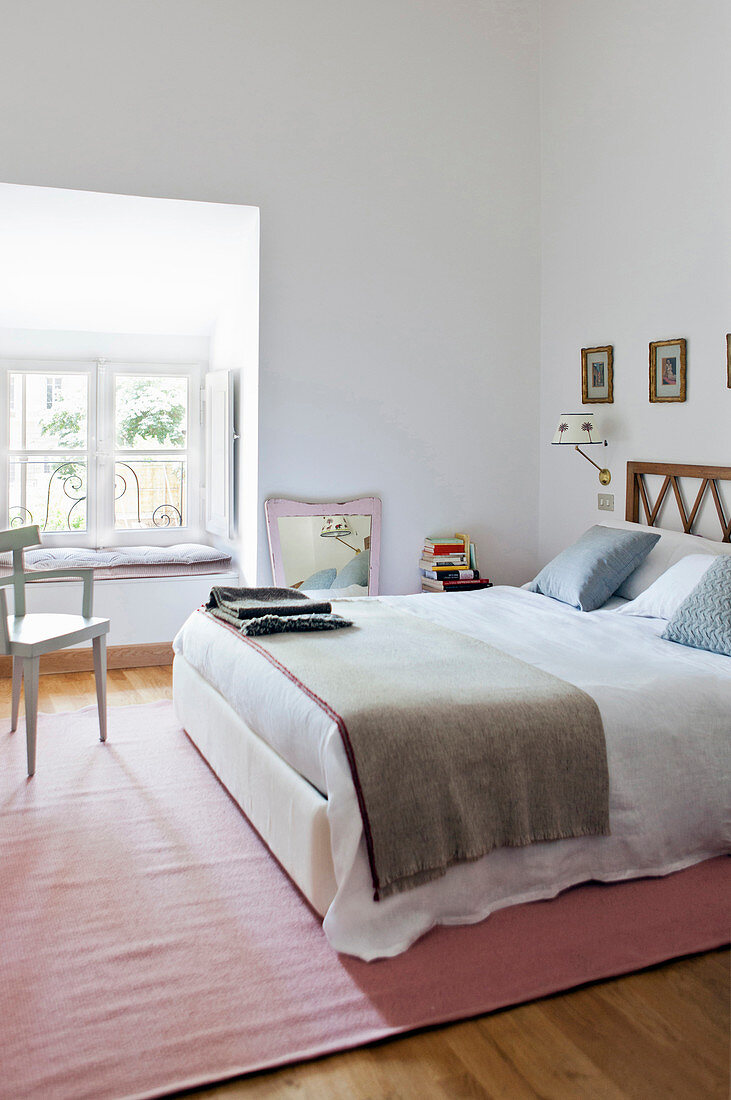 White walls, double bed and pink rug in bright, feminine bedroom