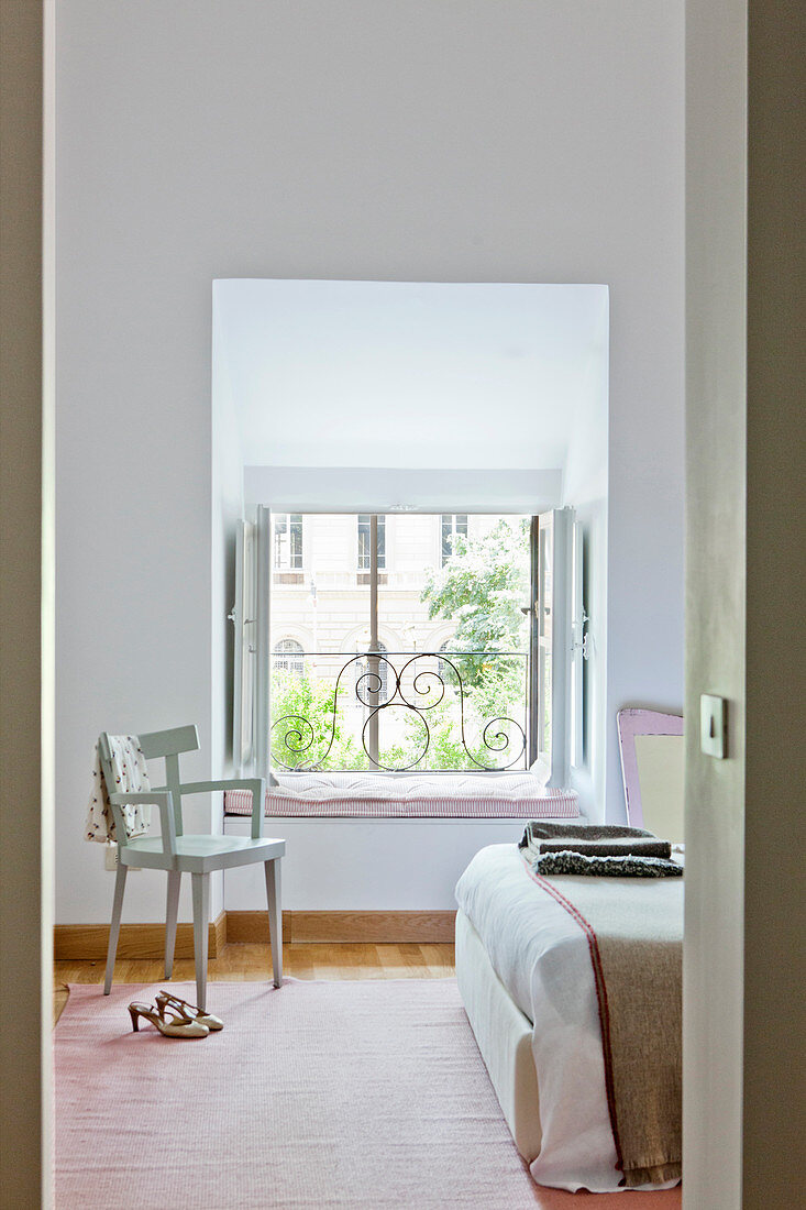 Helles feminines Schlafzimmer mit rosa Teppich und Sitzpolster in Fensternische