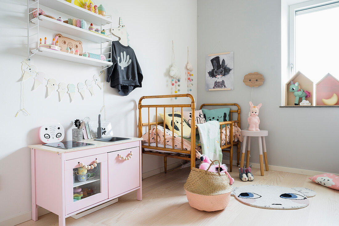Rosa Kinderküche neben Kinderbett in pastellfarbenem Mädchenzimmer