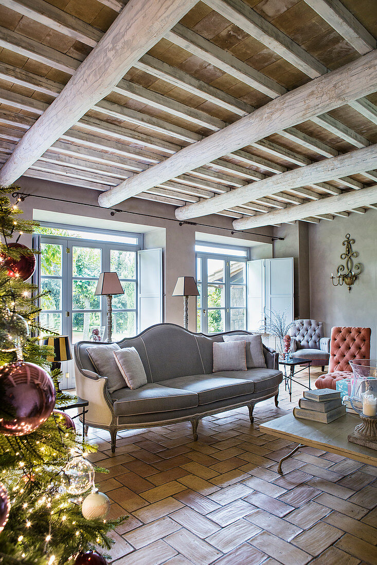 Christmas tree and grey sofa in living room of renovated farmhouse