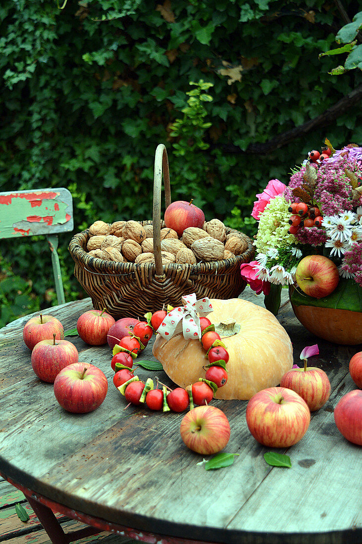 Herbstdeko mit Äpfeln, Walnüssen, Kürbis und Herbststrauß