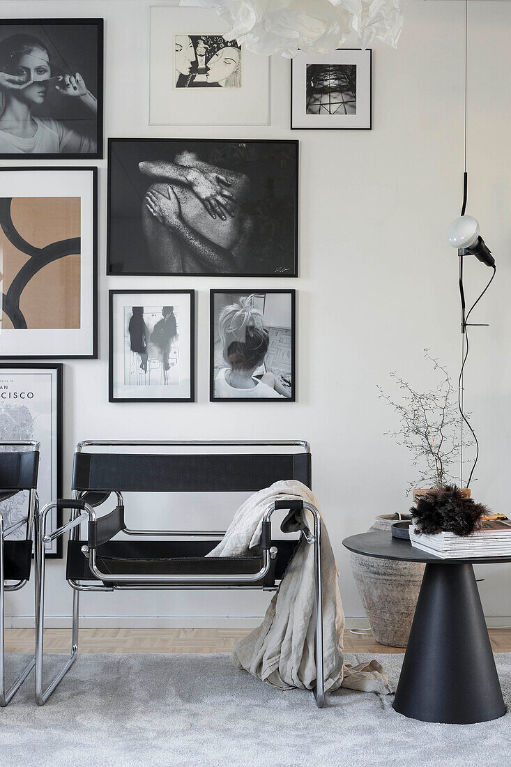 Designer chairs below gallery of pictures on wall in masculine living room