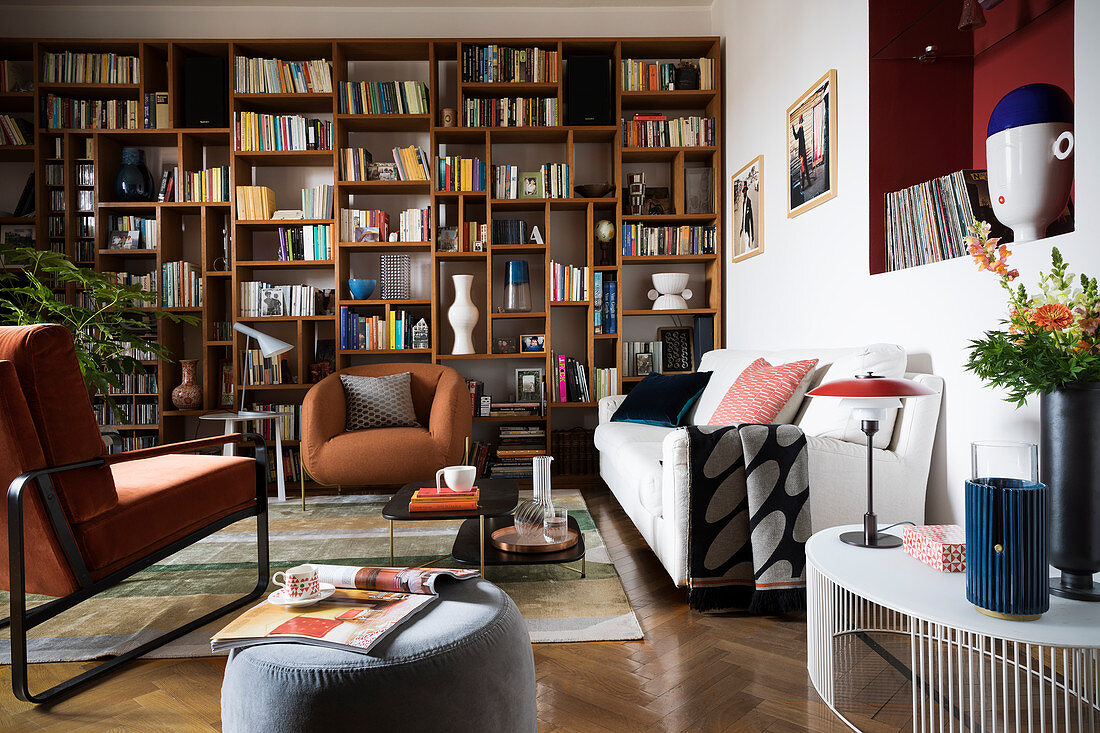 Wohnzimmer im Stilmix mit großem Bücherregal entlang einer Wand