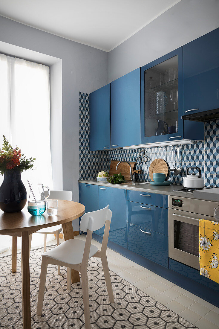 Runder Esstisch in der Wohnküche mit blauer Küchezeile