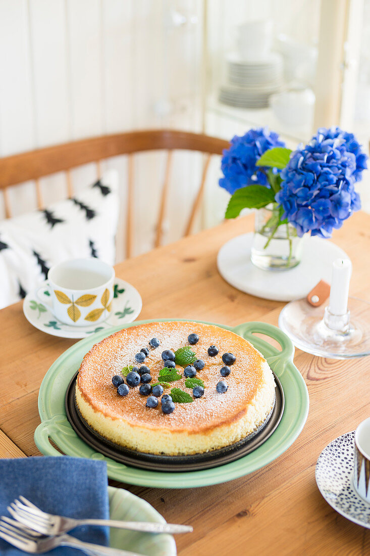 Kuchen mit Blaubeeren und Hortensien auf gedecktem Tisch