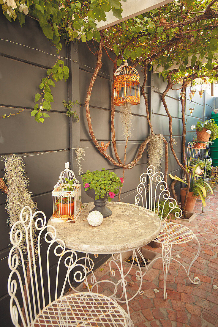 Romantische Gartenmöbel aus Metall an der Wand unter der Pergola