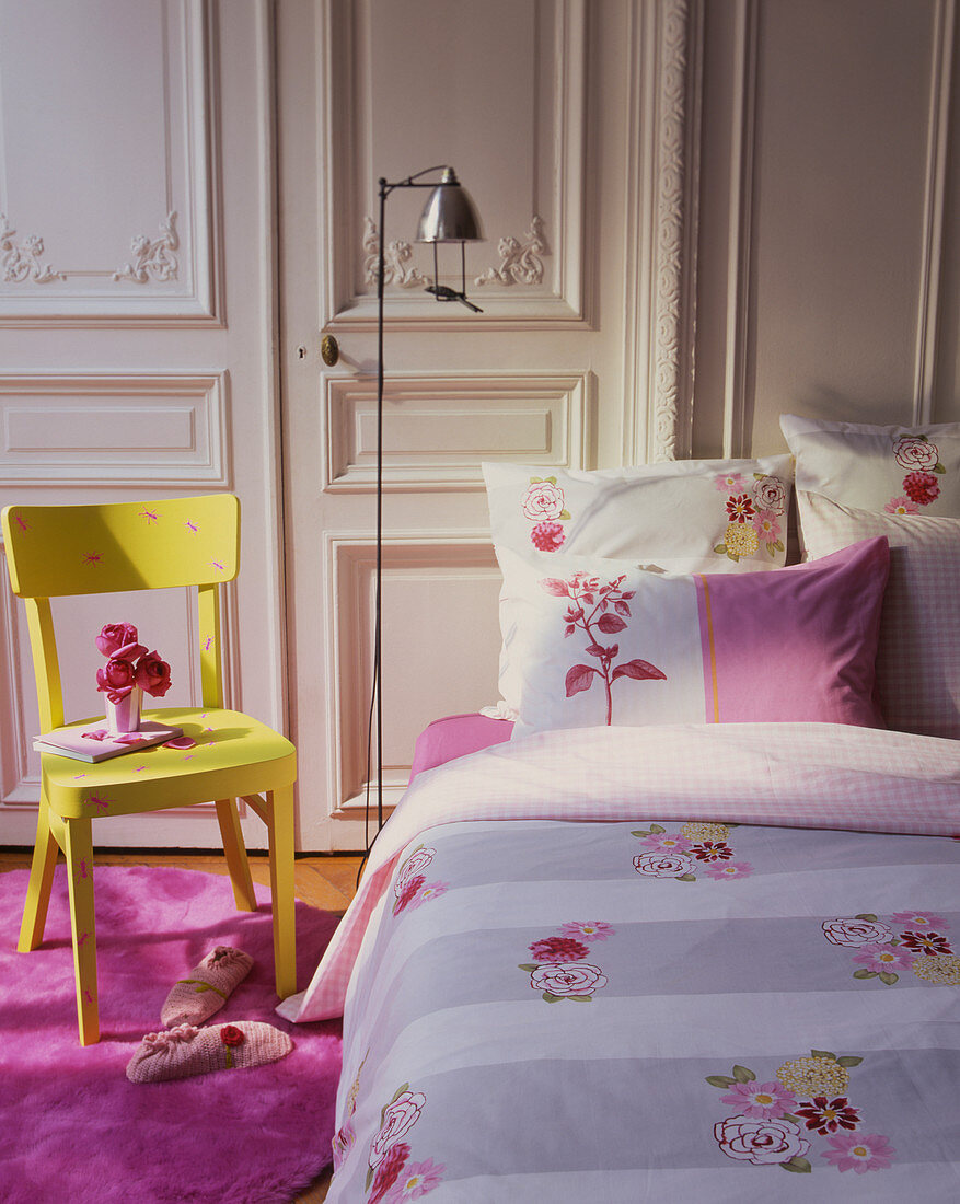 Feminines Schlafzimmer mit rosa Teppich, gelbem Stuhl und Stehlampe
