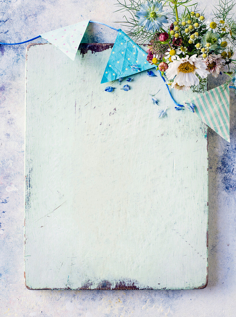 White-painted wooden board decorated with bunting and wildflowers