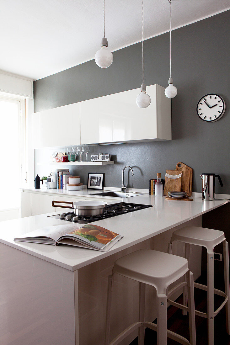 Küche mit weißen Hochglanzschränken und grauen Wänden