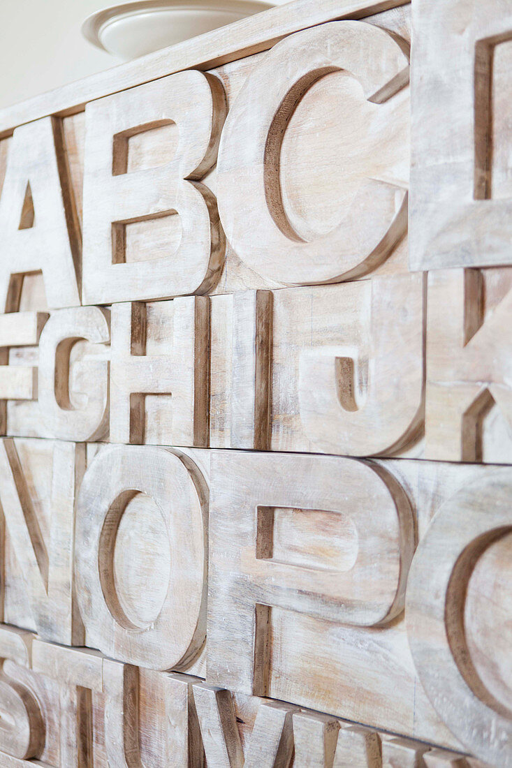 Detailansicht von Holzkommode mit geschnitzten Buchstaben