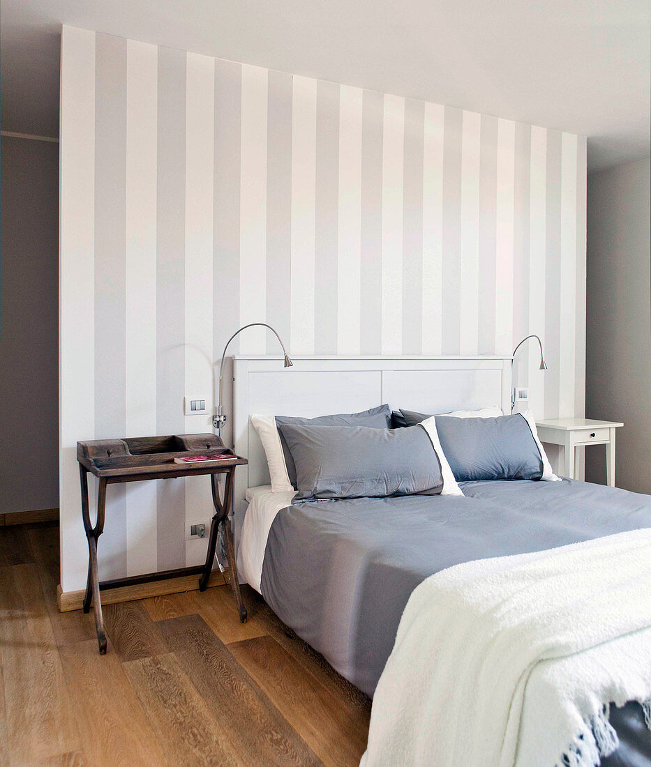 Double bed against grey-and-white striped partition