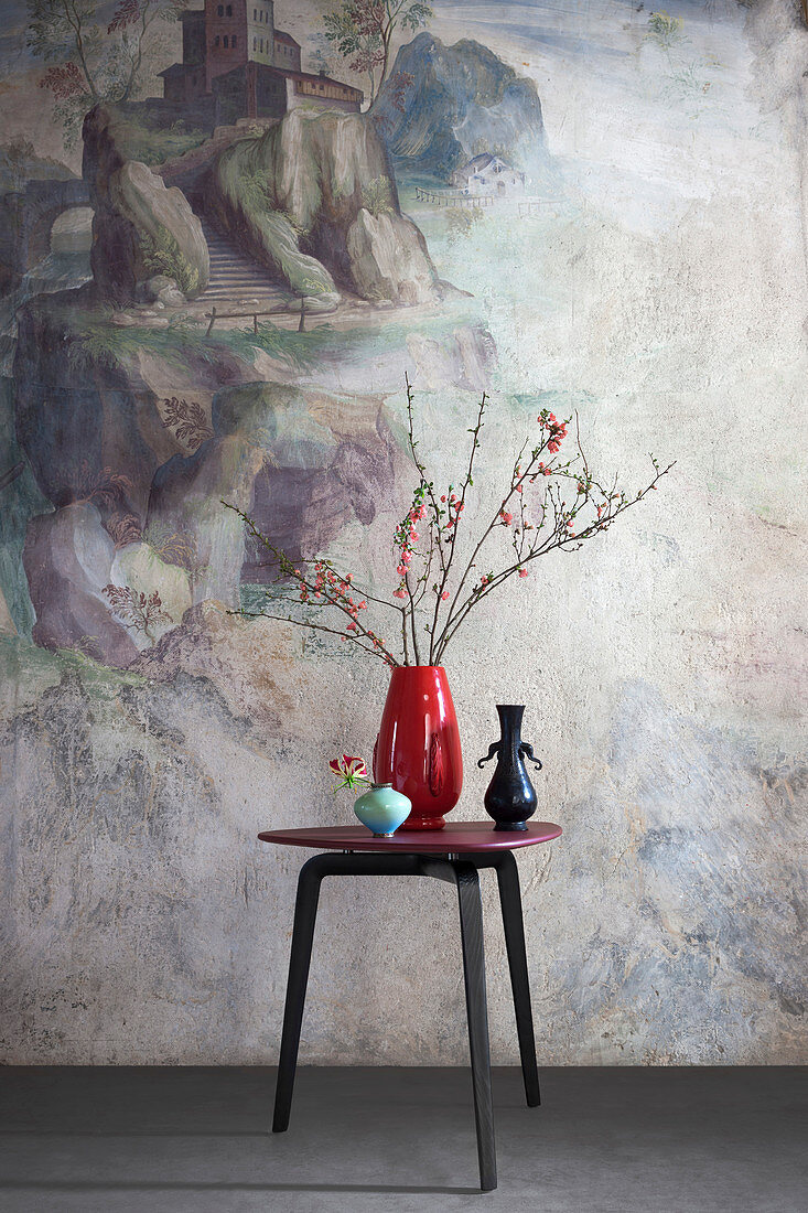Three vases on designer table in front of mural
