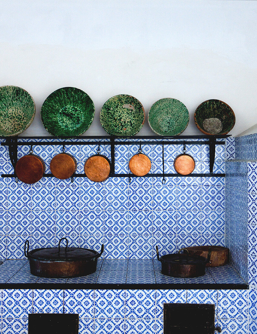 Blau-weiß geflieste Landhausküche mit antiken Keramikschalen und alten Kupfertöpfen