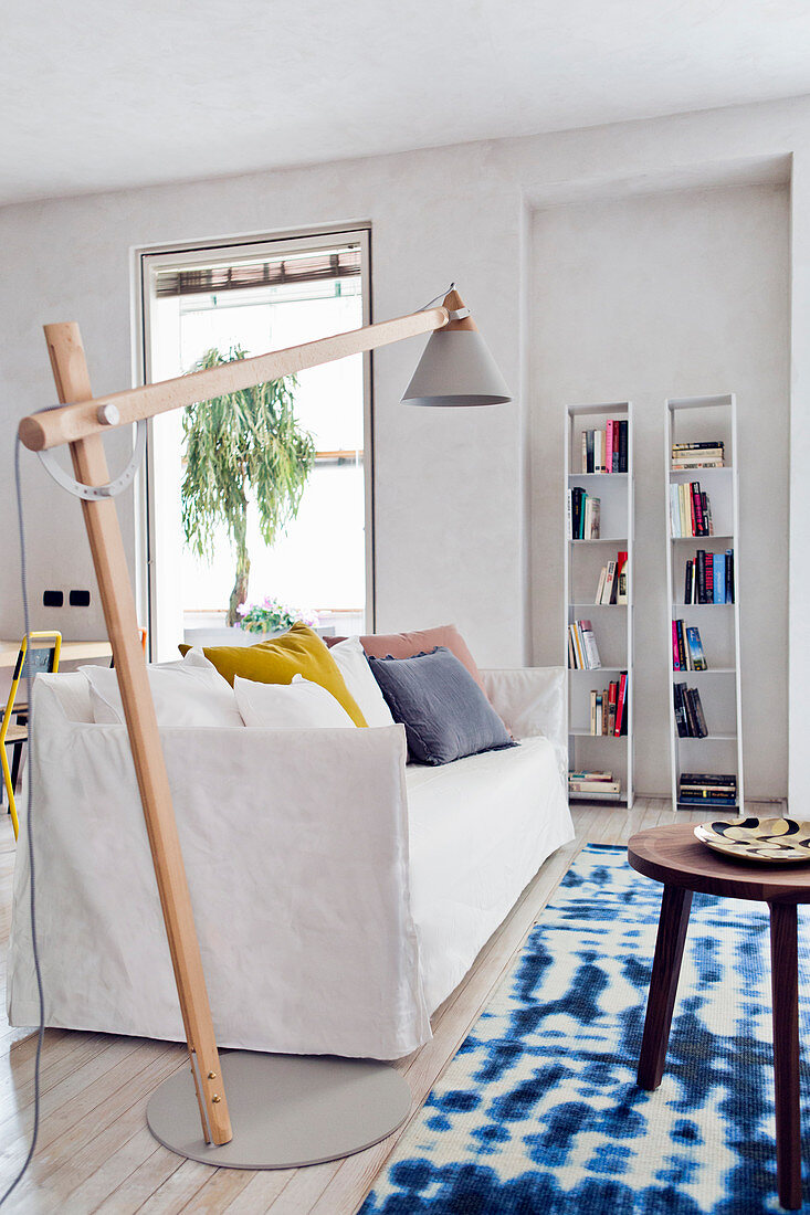 Modernes Wohnzimmer mit Sofa, schwenkbarer Stehlampe und blau-weißem Teppich