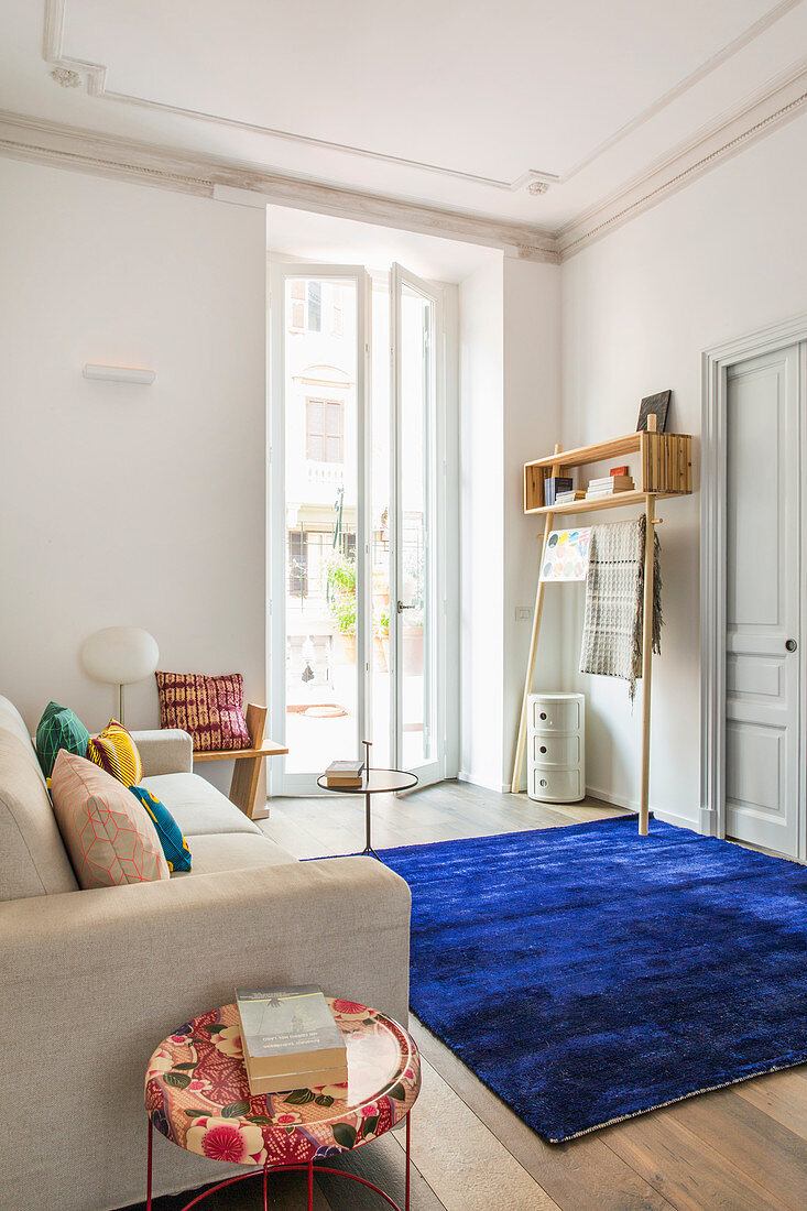 Dark blue rug providing a splash of colour in white living room of period apartment